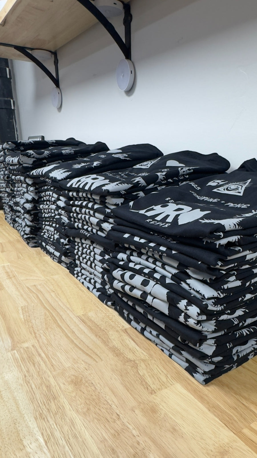 Large completed stack of custom screen printed black shirts